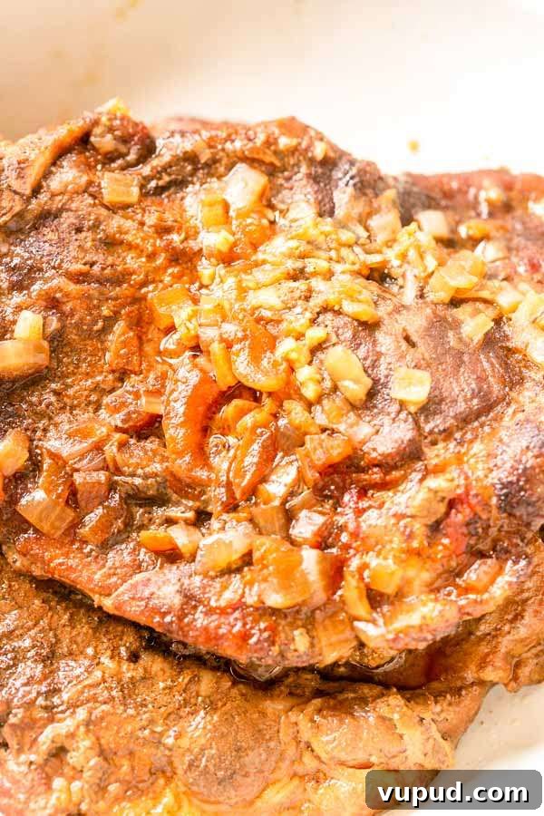 Juicy Pork Shoulder Steak in the Instant Pot: Quick Tender Recipe 8 Close up of a juicy pork shoulder steak topped with onion cooked in an Instant Pot.