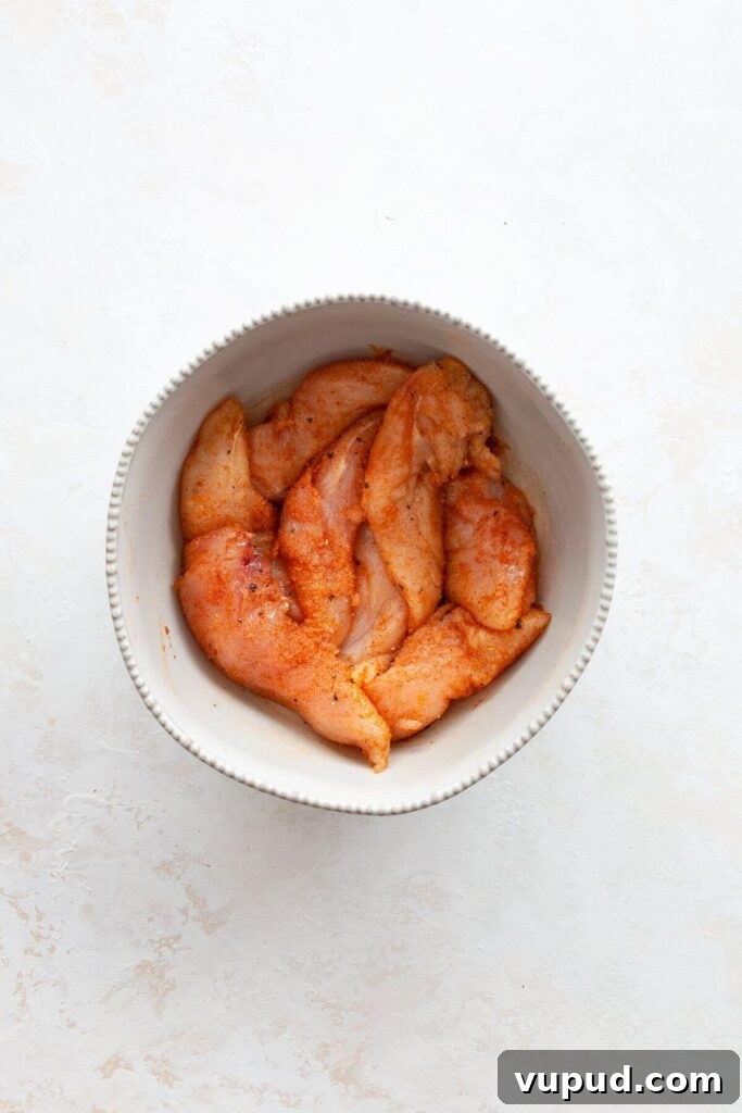 Crispy Air Fryer Chicken Tenders Without Breading 5 chicken tenders in a mixing bowl with seasonings