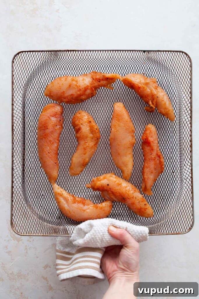 Crispy Air Fryer Chicken Tenders Without Breading 6 uncooked chicken tenders without breading in an air fryer basket