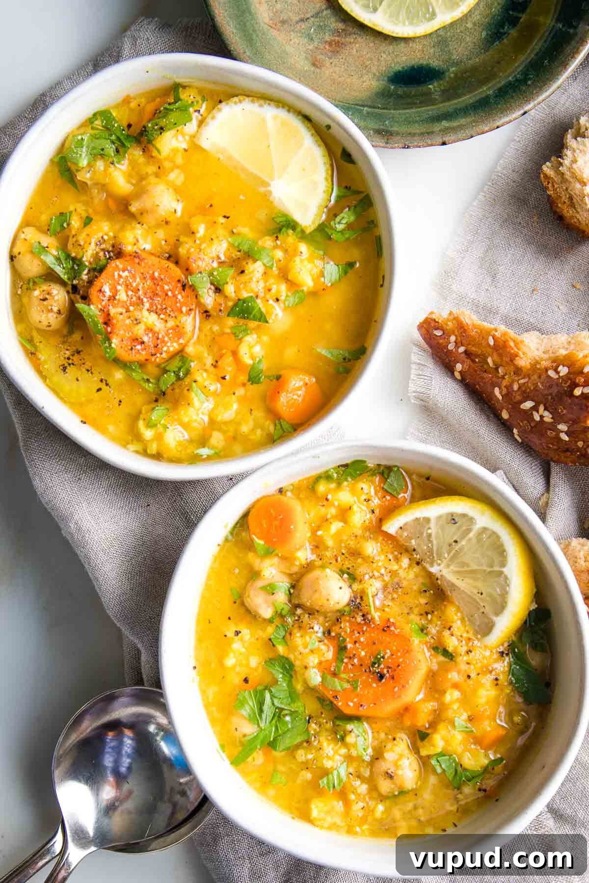 Lemony Vegan Chickpea and Rice Soup Recipe 2 Two bowls of chunky chickpea, vegetable rice soup with lemon.