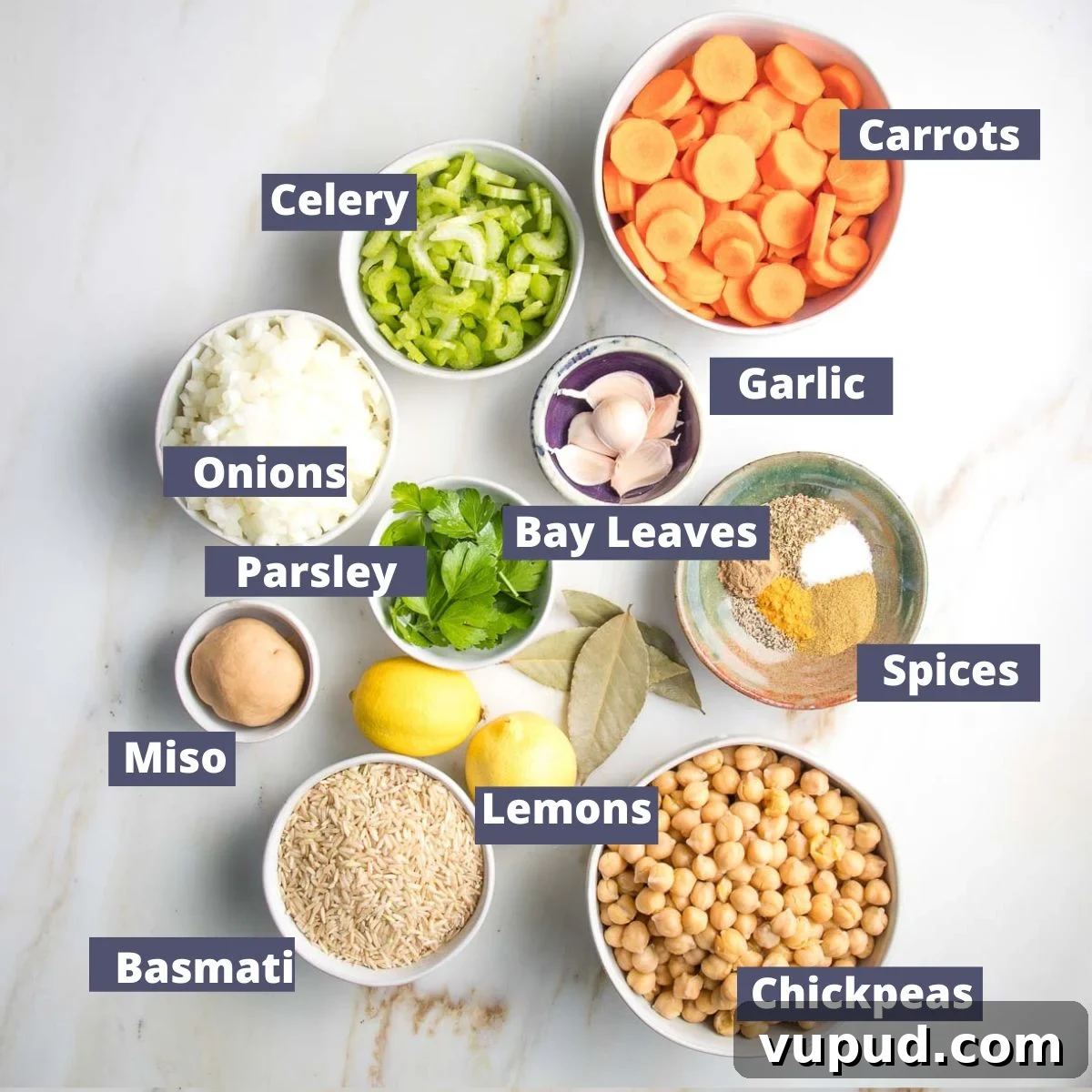 Lemony Vegan Chickpea and Rice Soup Recipe 4 Labeled ingredients: carrots, celery, onions, garlic, spices, chickpeas, basmati rice, miso, lemons, parsley, bay leaves.