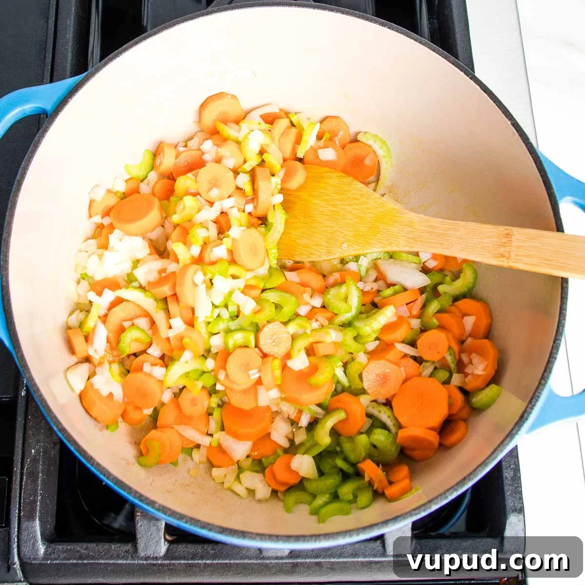 Lemony Vegan Chickpea and Rice Soup Recipe 5 Dutch oven filled with carrots, celery, onions and a wooden spoon.
