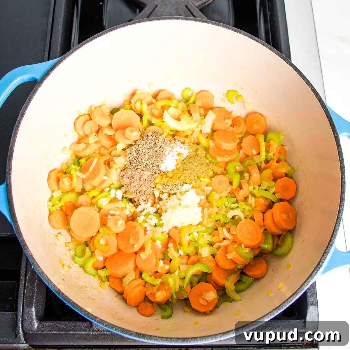 Lemony Vegan Chickpea and Rice Soup Recipe 6 Dutch oven with sauteed carrots, onion, and celery with spices and garlic on top.