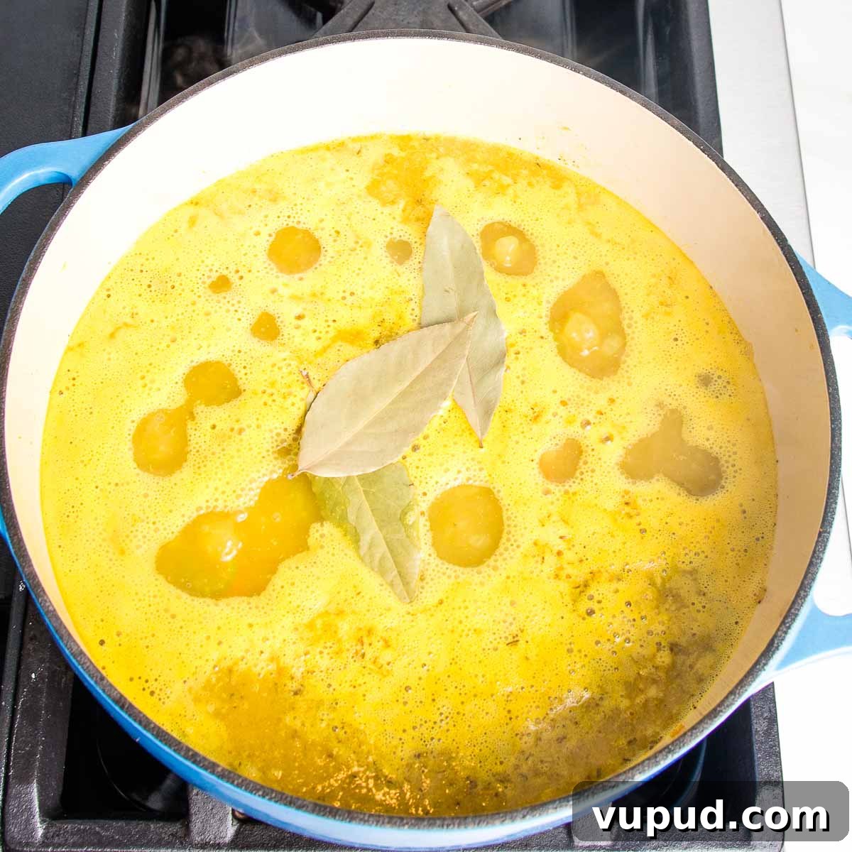 Lemony Vegan Chickpea and Rice Soup Recipe 7 Dutch oven with yellow broth and bay leaves.