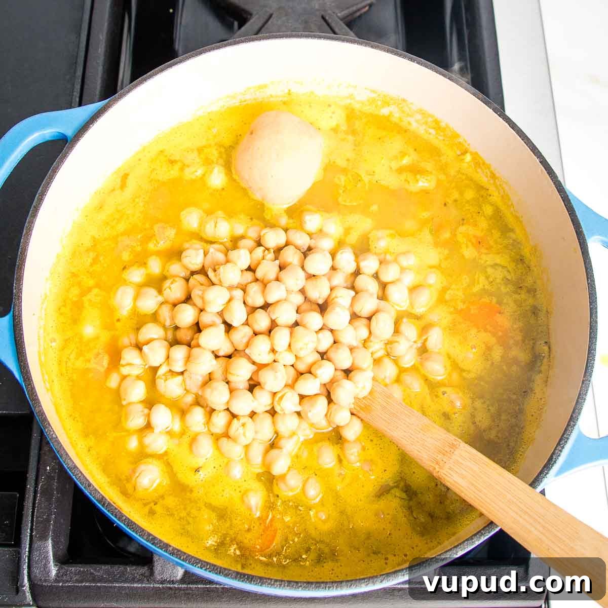 Lemony Vegan Chickpea and Rice Soup Recipe 8 Dutch oven with yellow broth, chickpeas and a scoop of miso paste.