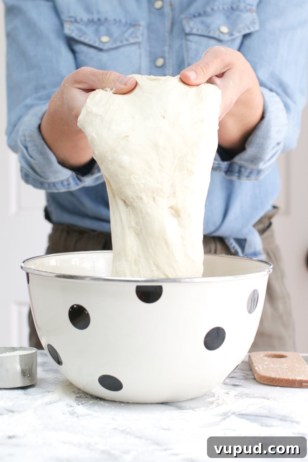 72-Hour Pizza Dough Recipe from Baking Steel 11 holding the 72 hour pizza dough after fermentation to show its elasticity
