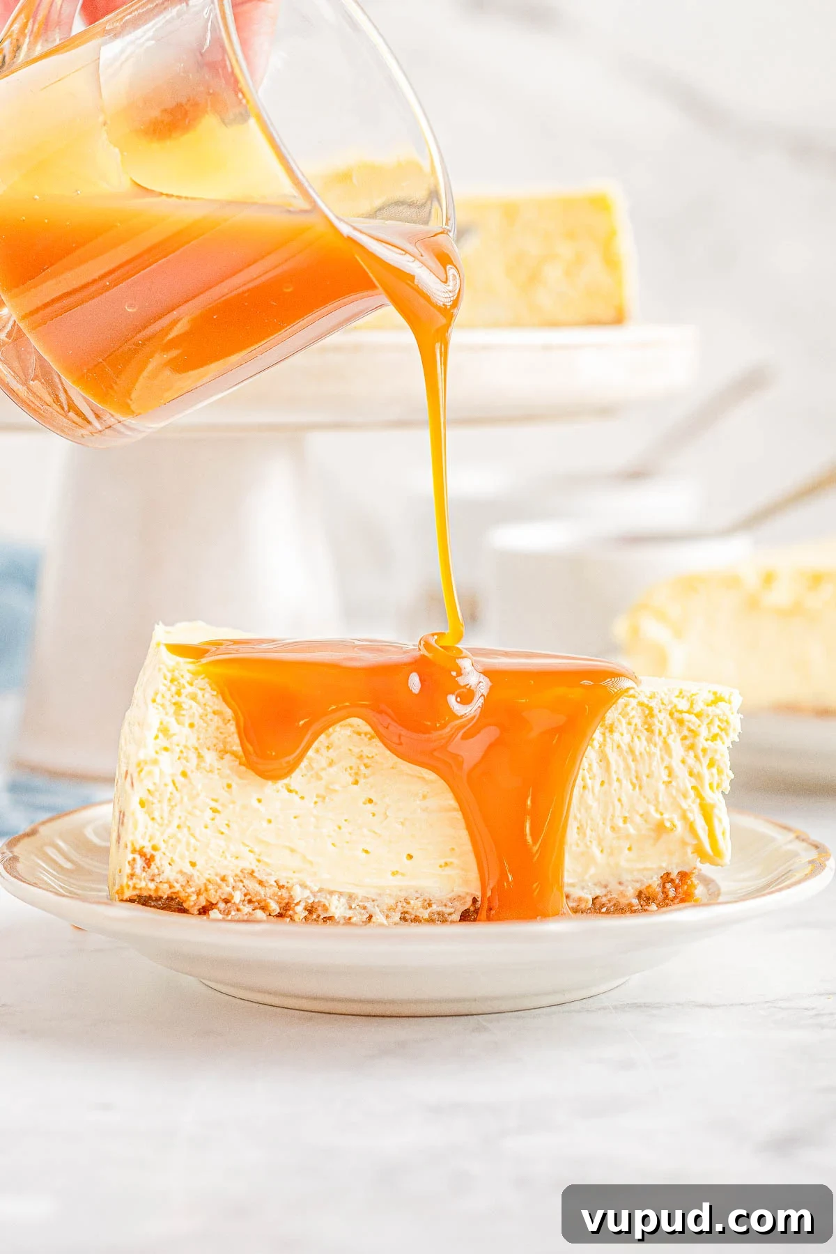 Classic New York Cheesecake Recipe: Creamy Oven-Baked Slice 2 Caramel sauce being poured over a slice of New York-style cheesecake.