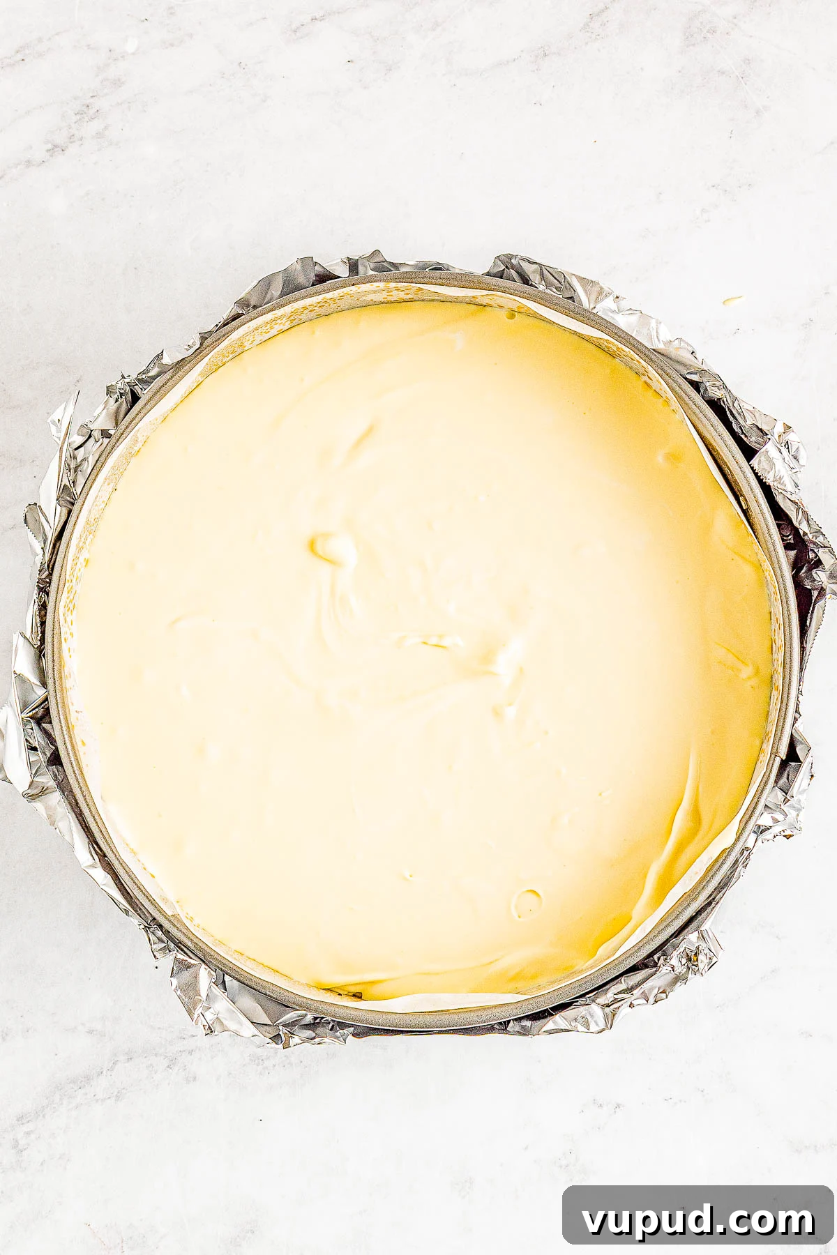 Classic New York Cheesecake Recipe: Creamy Oven-Baked Slice 16 A freshly prepared cheesecake in a springform pan, wrapped in foil and ready to bake.