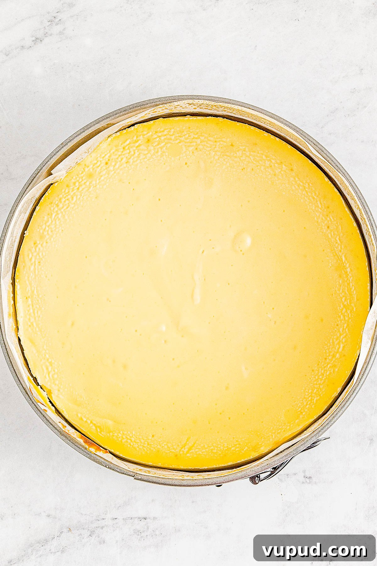 Classic New York Cheesecake Recipe: Creamy Oven-Baked Slice 18 A freshly baked, smooth cheesecake in a round springform pan.