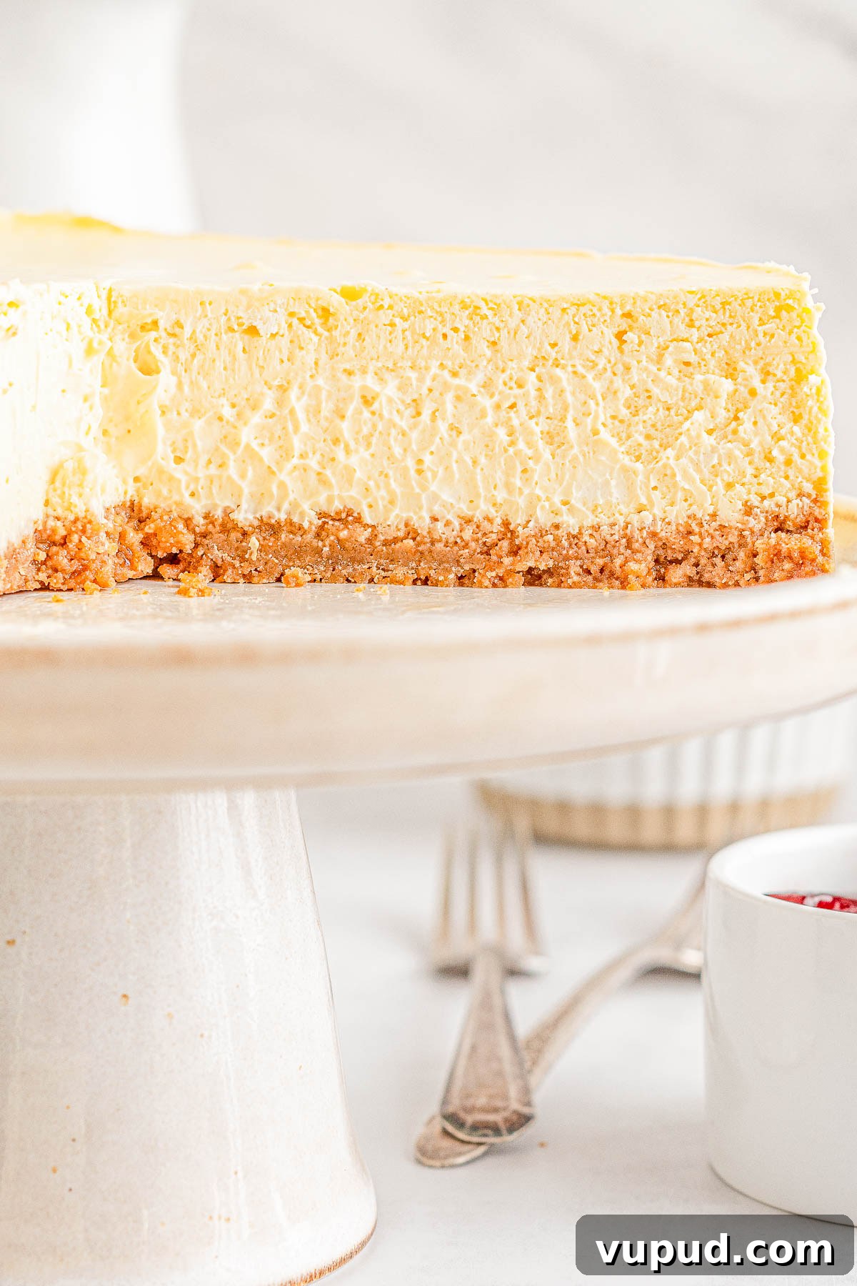 Classic New York Cheesecake Recipe: Creamy Oven-Baked Slice 4 Side view of a classic New York cheesecake with a slice missing.
