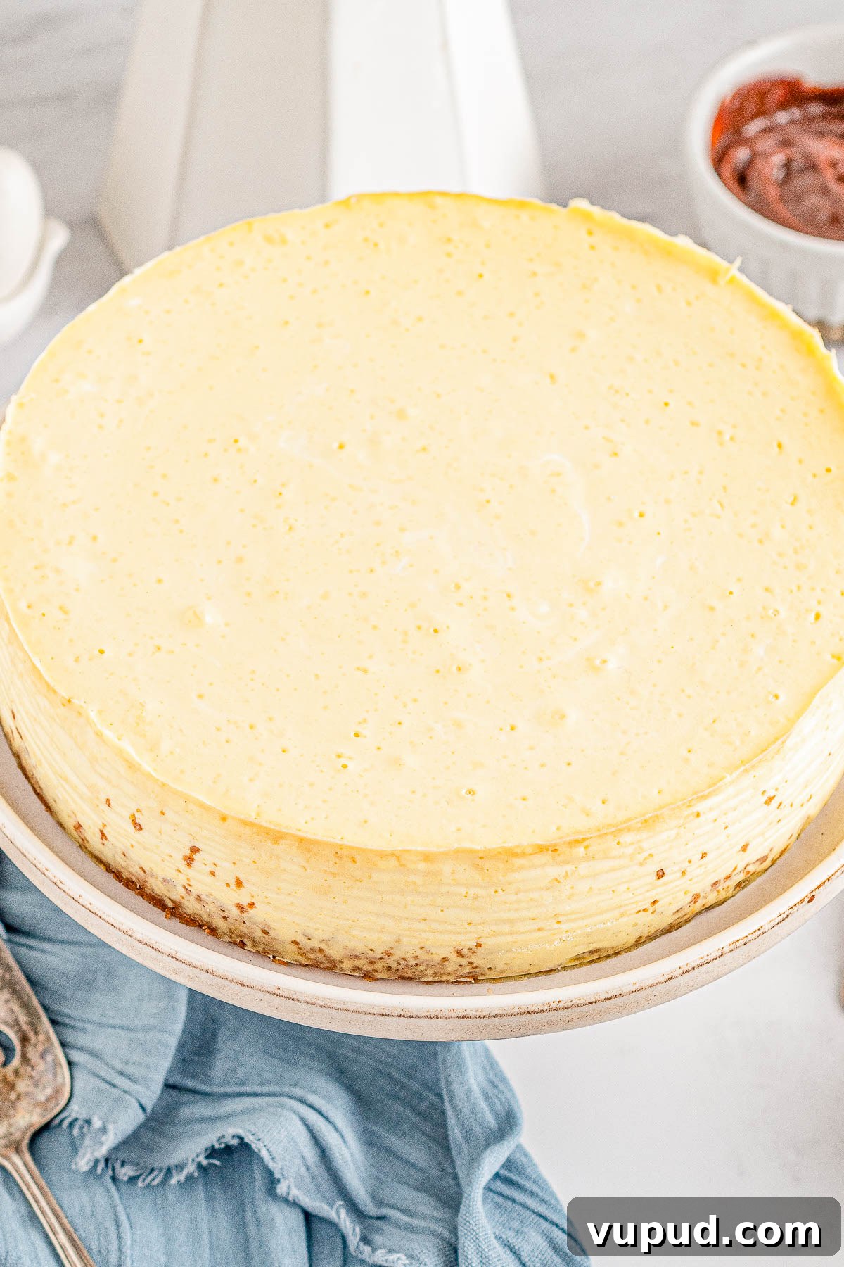 Classic New York Cheesecake Recipe: Creamy Oven-Baked Slice 10 A whole classic New York cheesecake on a plate.